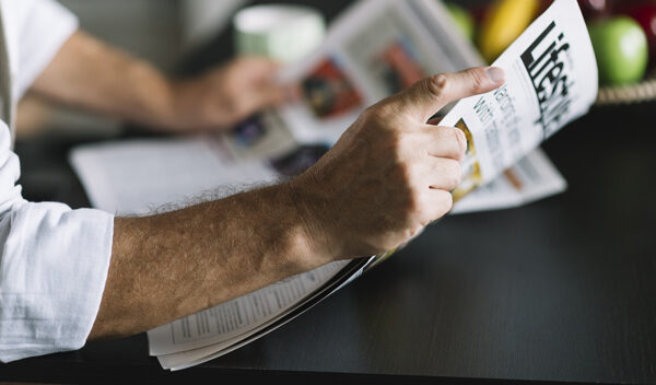 man-s-hand-holding-newspaper_23-2147901151